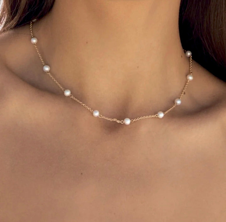 a close up of a woman wearing a necklace with pearls