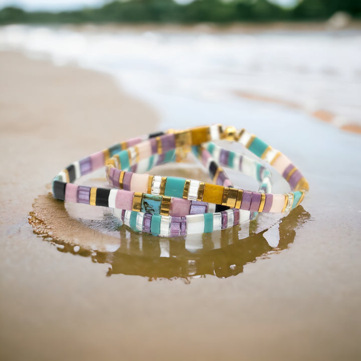 a couple of bracelets sitting on top of a sandy beach