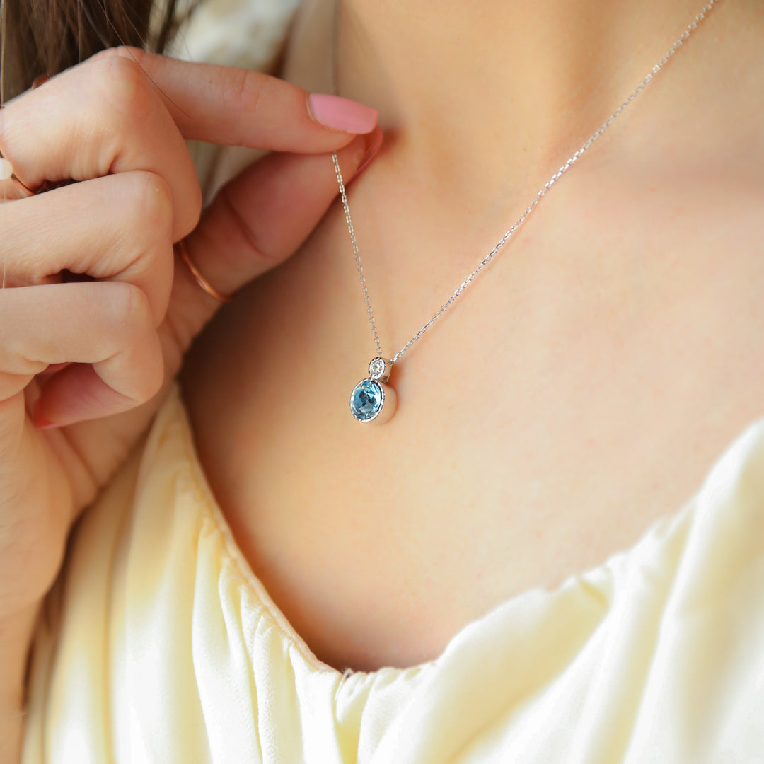 a woman wearing a necklace with a blue stone