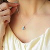a woman wearing a necklace with a blue stone