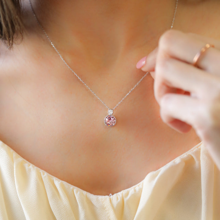 a woman wearing a necklace with a pink flower on it