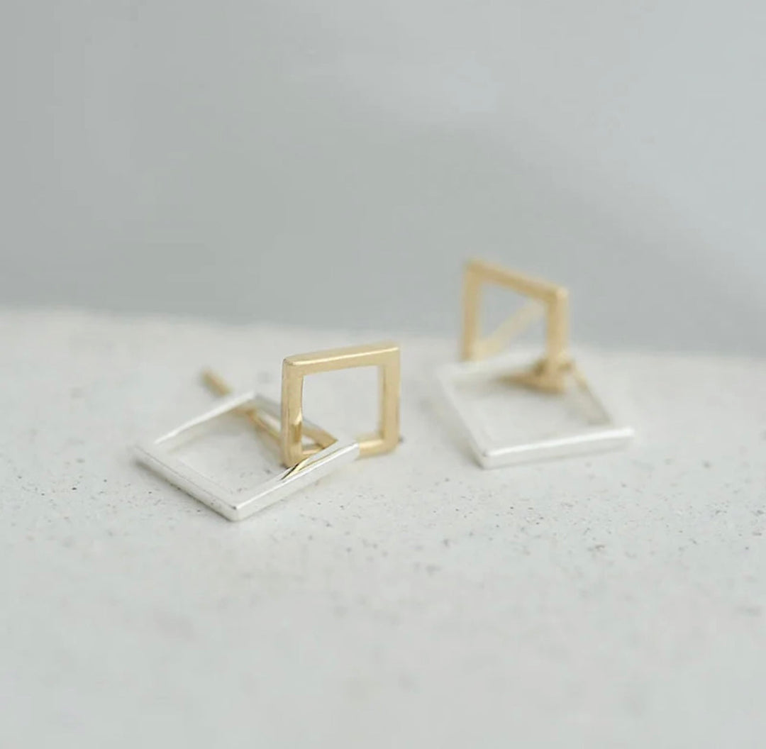 a pair of gold and silver square earrings