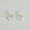 a pair of gold and silver earrings on a white surface