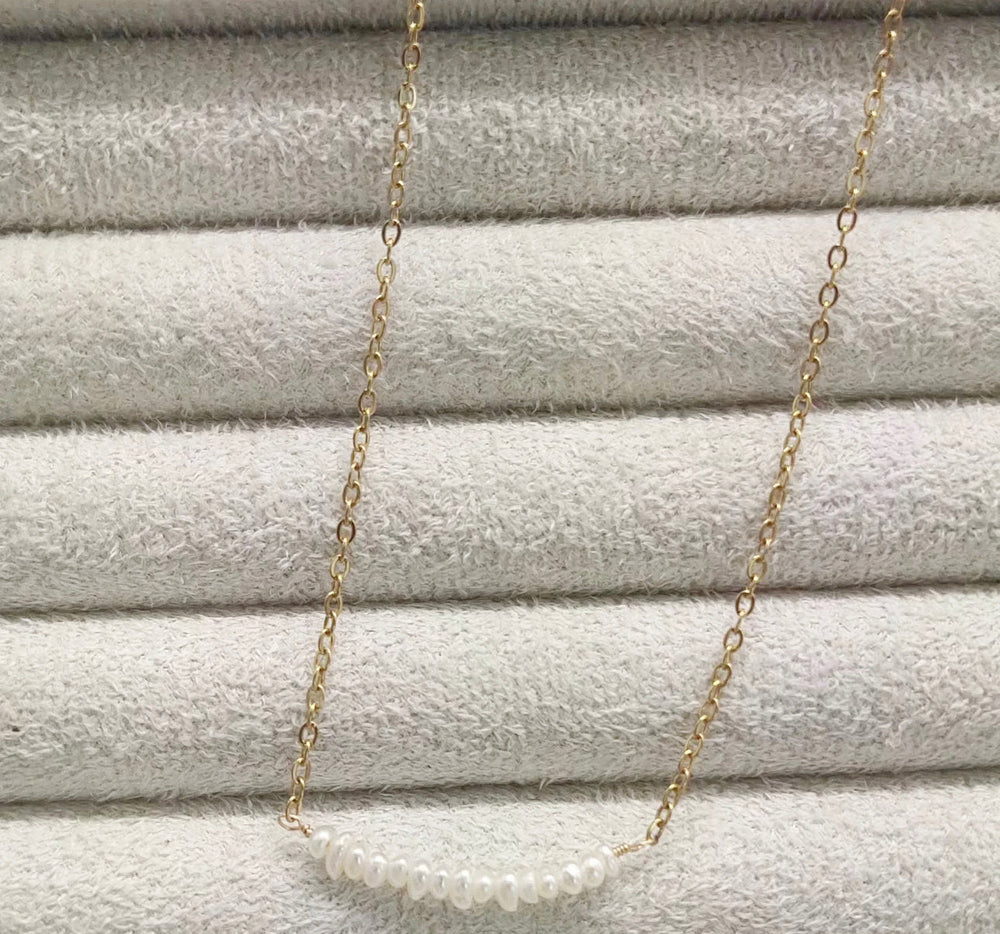 a gold chain with a white pearl on it
