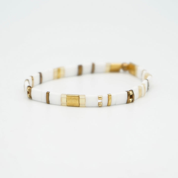 a white and gold bracelet on a white background