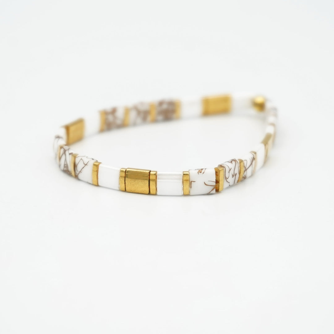 a white and gold bracelet on a white background