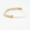 a white and gold bracelet on a white surface