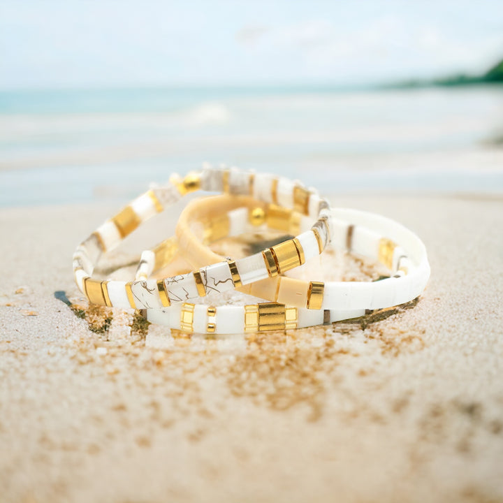 a couple of bracelets sitting on top of a sandy beach