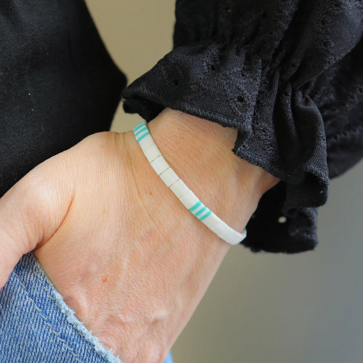 a person wearing a white bracelet with a blue stripe