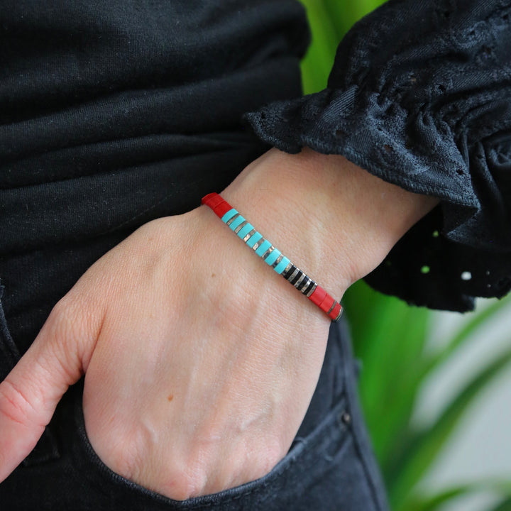 a woman wearing a red bracelet with blue beads