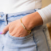a woman wearing a gold bracelet and jeans