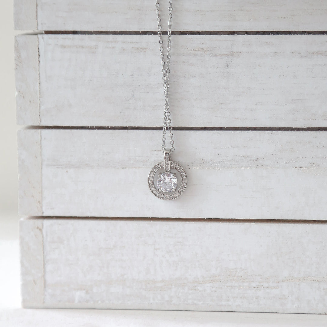 a white wooden box with a silver necklace on it