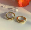 a pair of gold hoop earrings sitting on top of a table