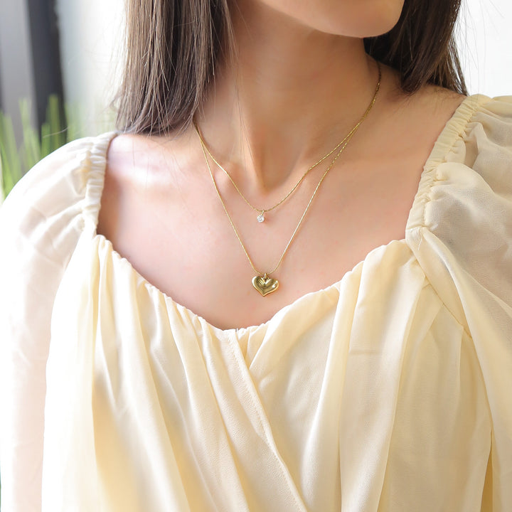 a woman wearing a yellow dress and a gold necklace