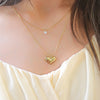 a close up of a woman wearing a necklace with a heart on it