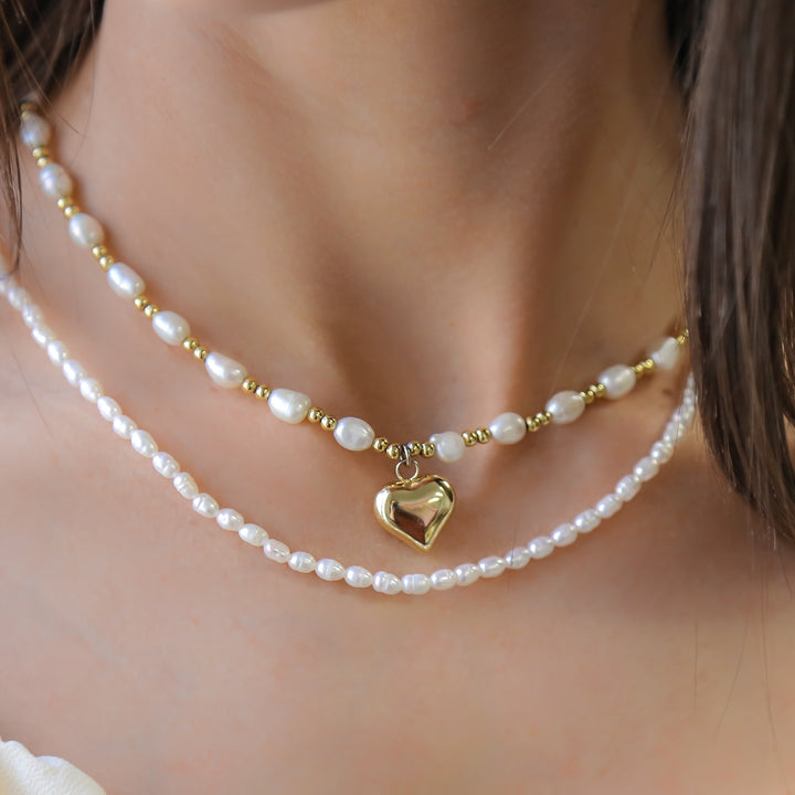 a woman wearing a pearl necklace with a heart charm