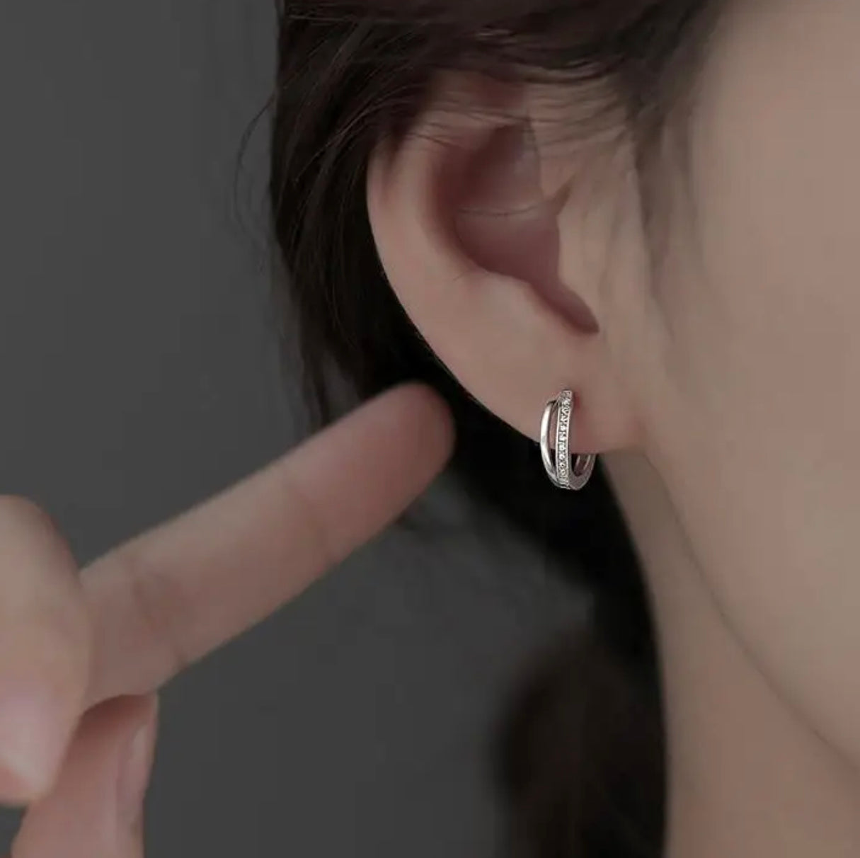 a close up of a person touching a pair of earrings