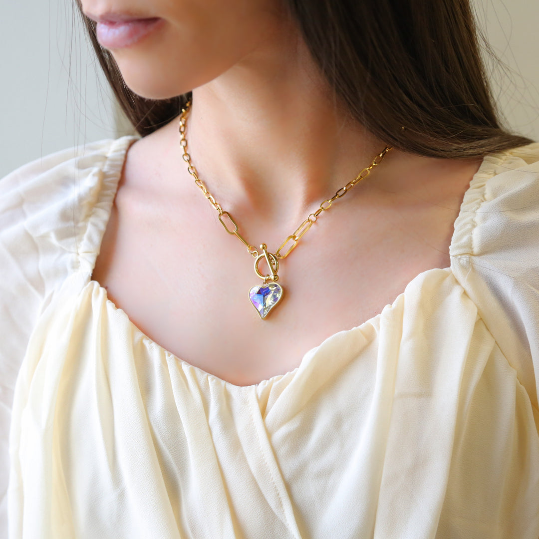 a woman wearing a necklace with a heart shaped pendant