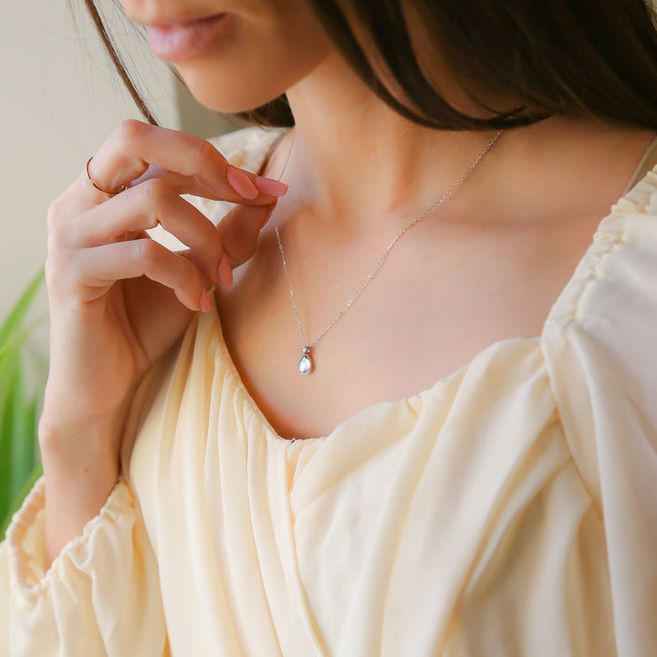 a woman in a white dress is holding a necklace