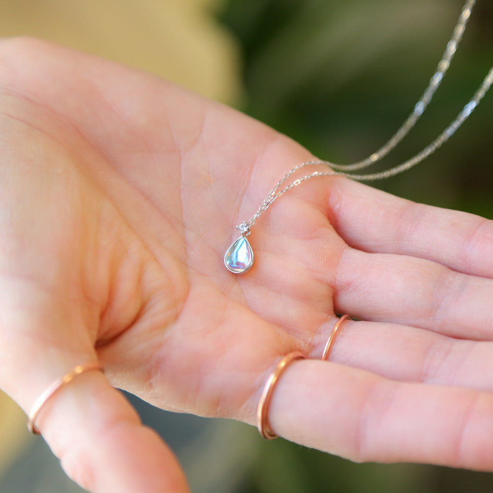 a person holding a tiny necklace in their hand