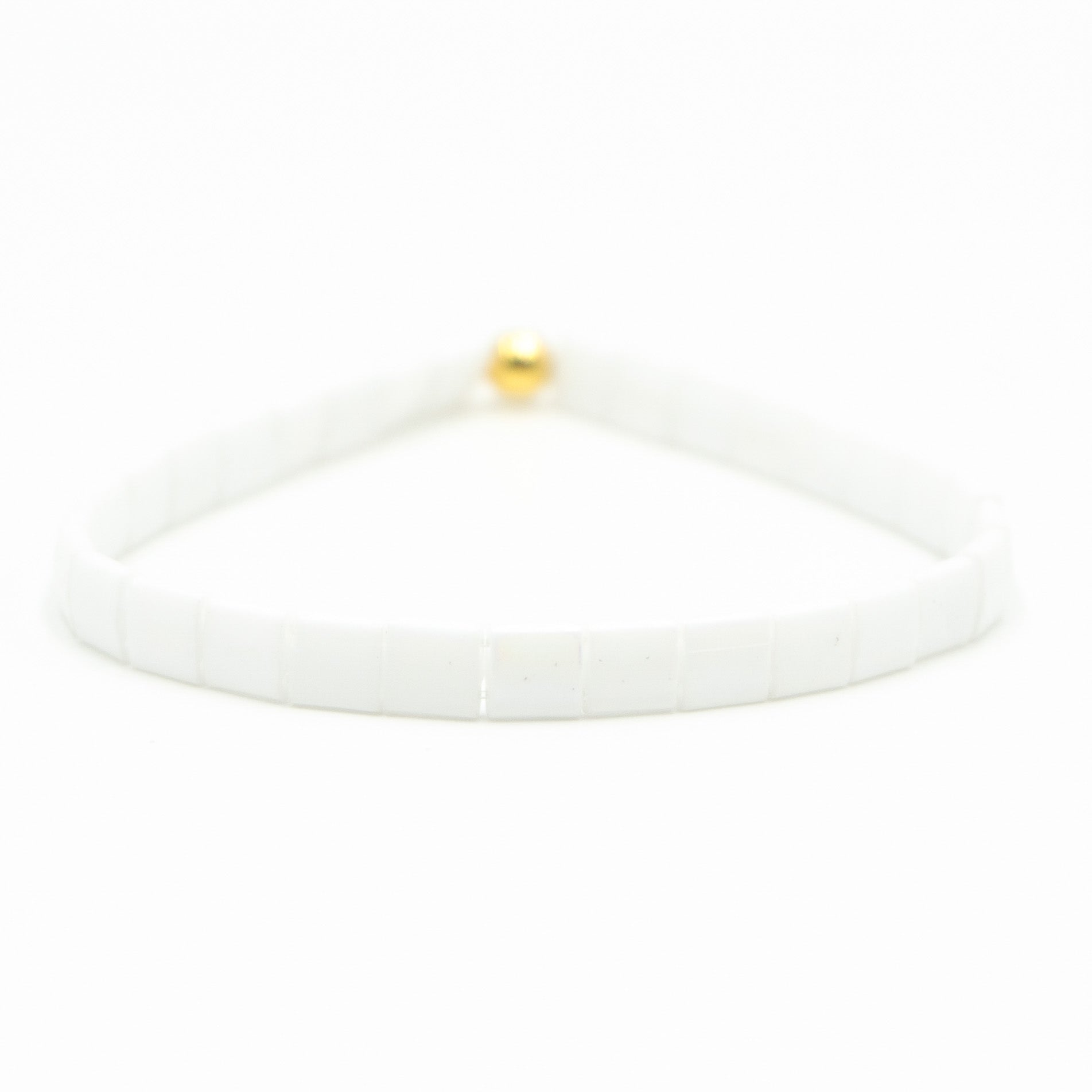 a white bracelet with a gold ball on it