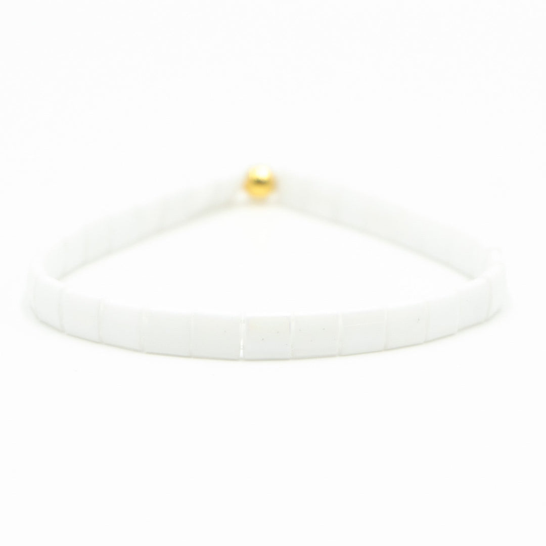 a white bracelet with a gold ball on it