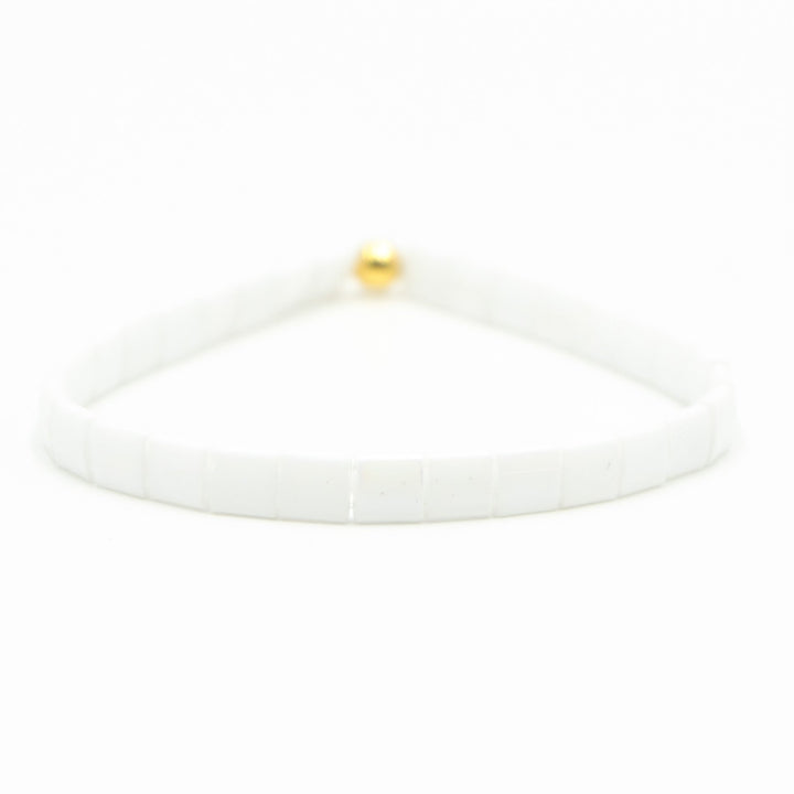 a white bracelet with a gold ball on it