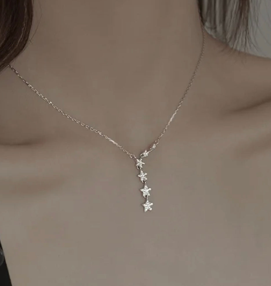 a woman wearing a silver necklace with stars on it