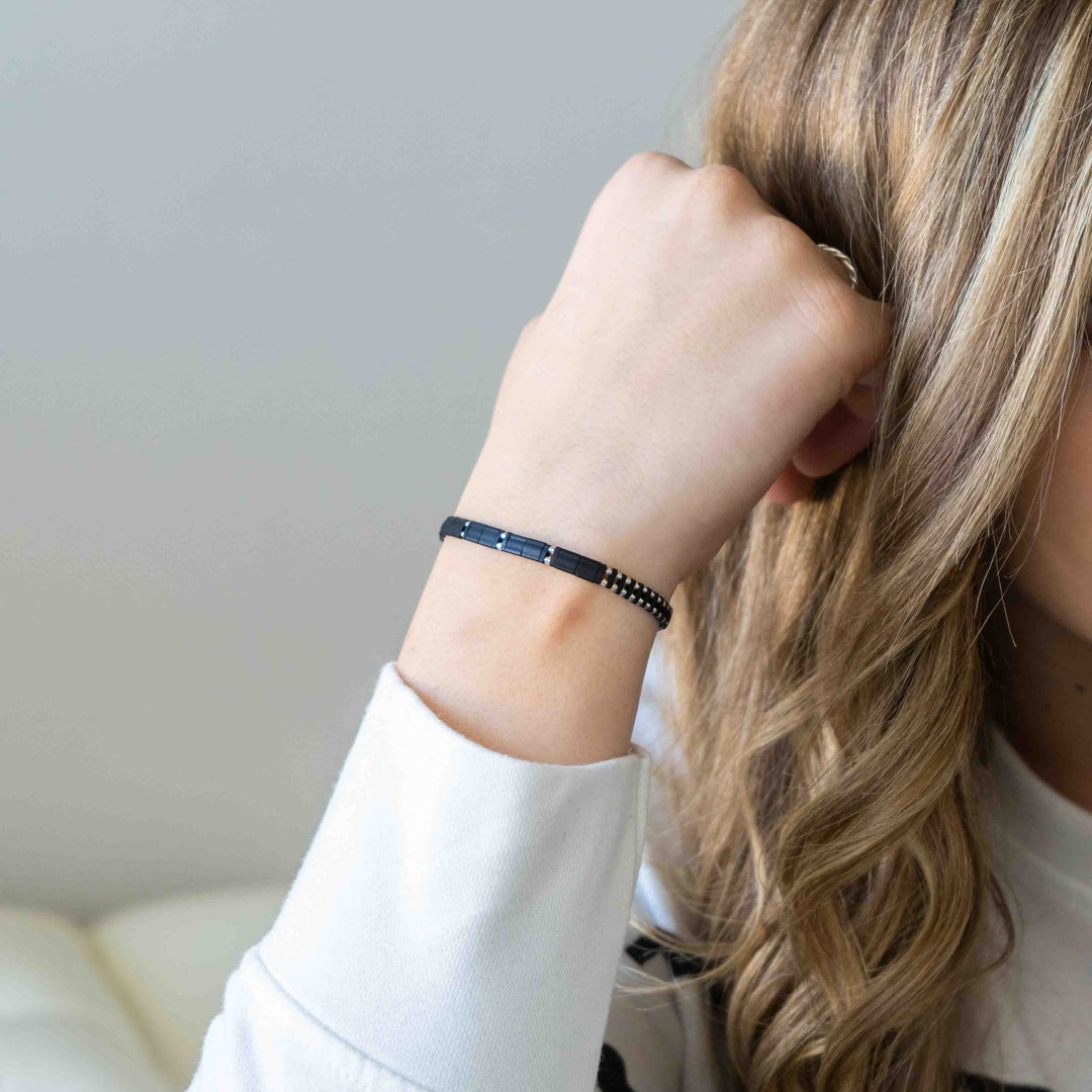 a woman wearing a black bracelet and a white shirt