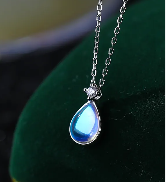 a necklace with a blue tear hanging from it