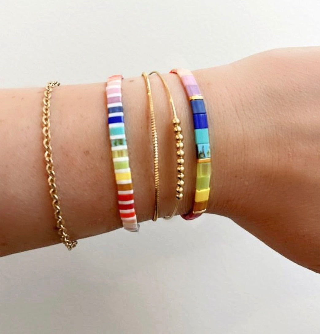 a woman's arm with four different colored bracelets on it