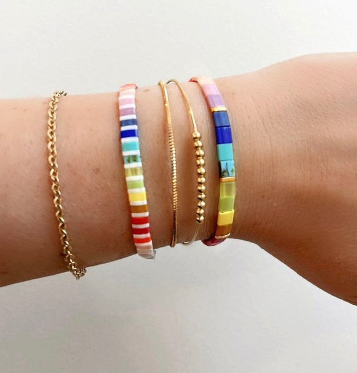 a woman's arm with four different colored bracelets on it