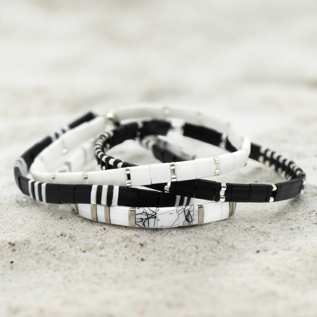 a couple of bracelets sitting on top of a sandy beach