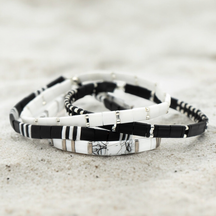 a couple of bracelets sitting on top of a sandy beach