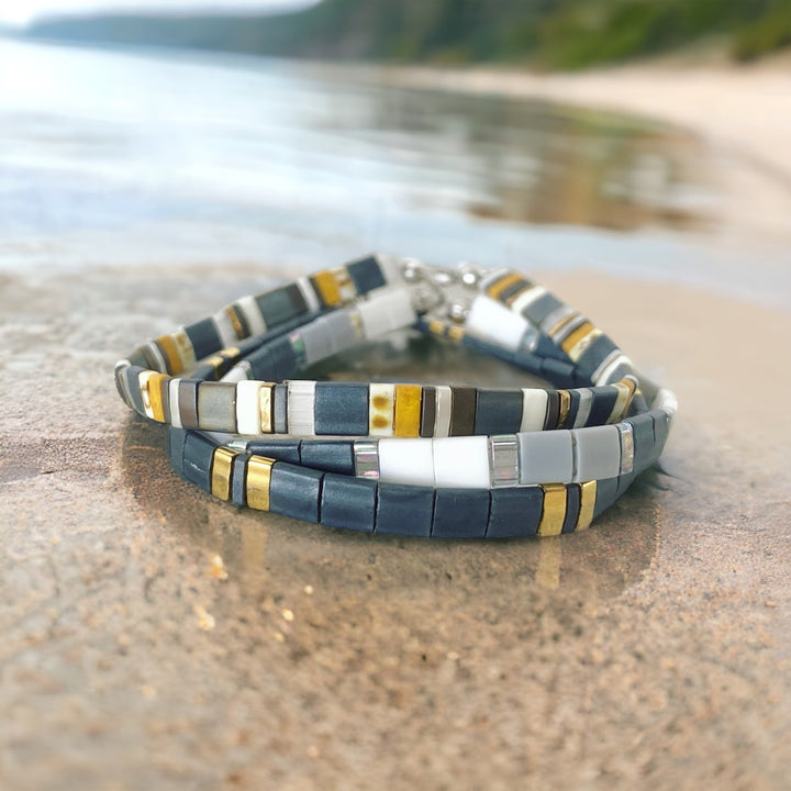 a couple of bracelets sitting on top of a sandy beach