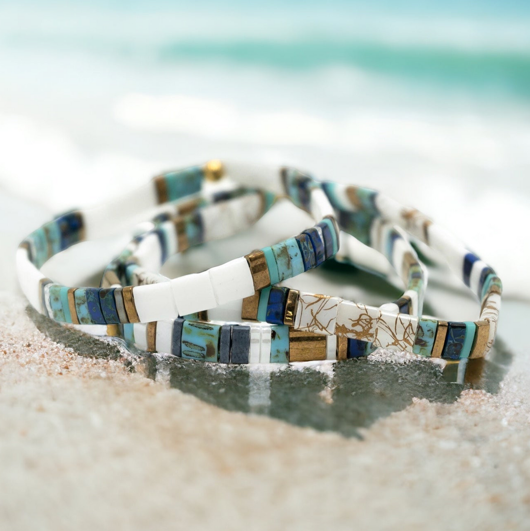 a couple of bracelets sitting on top of a sandy beach