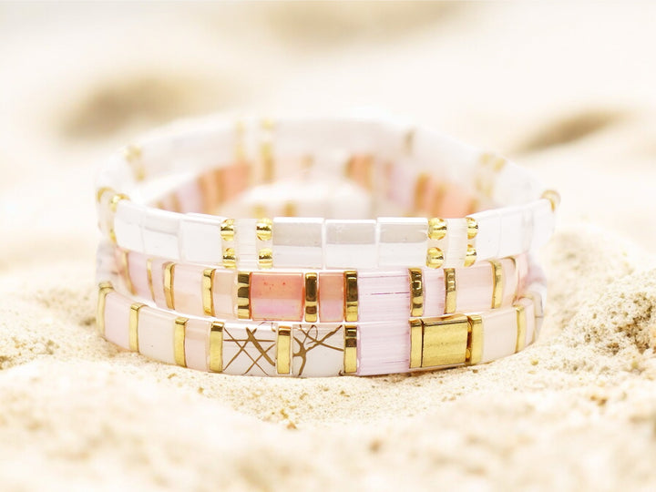 a couple of bracelets sitting on top of a sandy beach