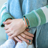 a woman wearing two different bracelets on her wrist