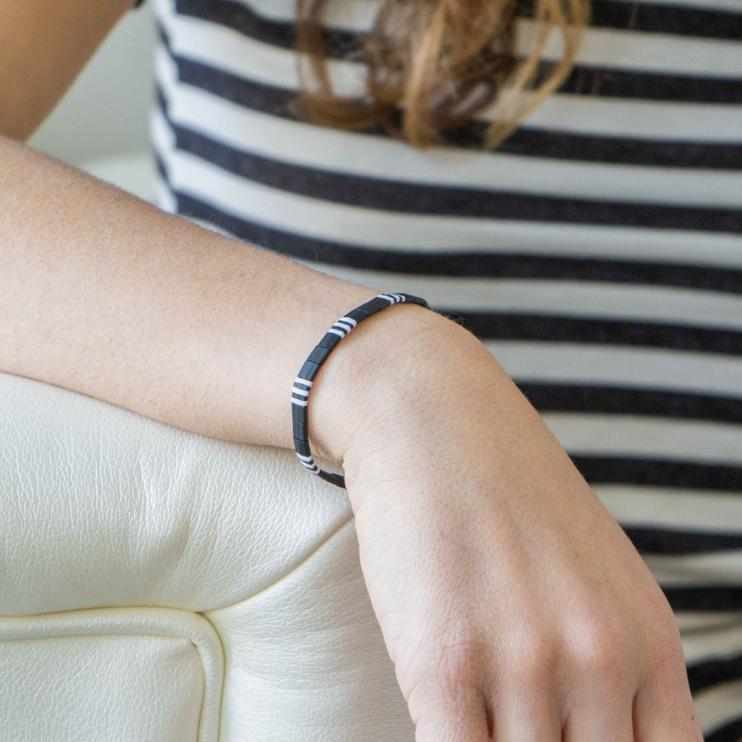 a woman wearing a black and white bracelet on her wrist