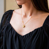 a woman wearing a black top and a gold heart necklace