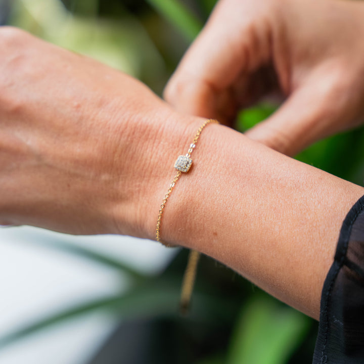 a woman wearing a gold bracelet with a diamond