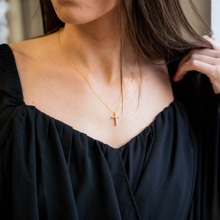 a woman wearing a necklace with a cross on it