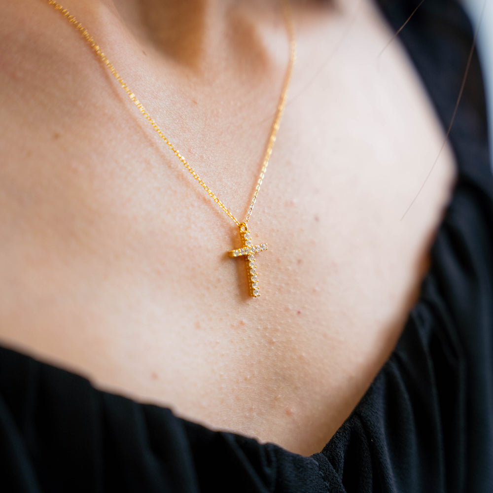 a woman wearing a necklace with a cross on it