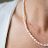 a close up of a woman wearing a pearl necklace