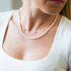 a woman wearing a necklace with pearls on it