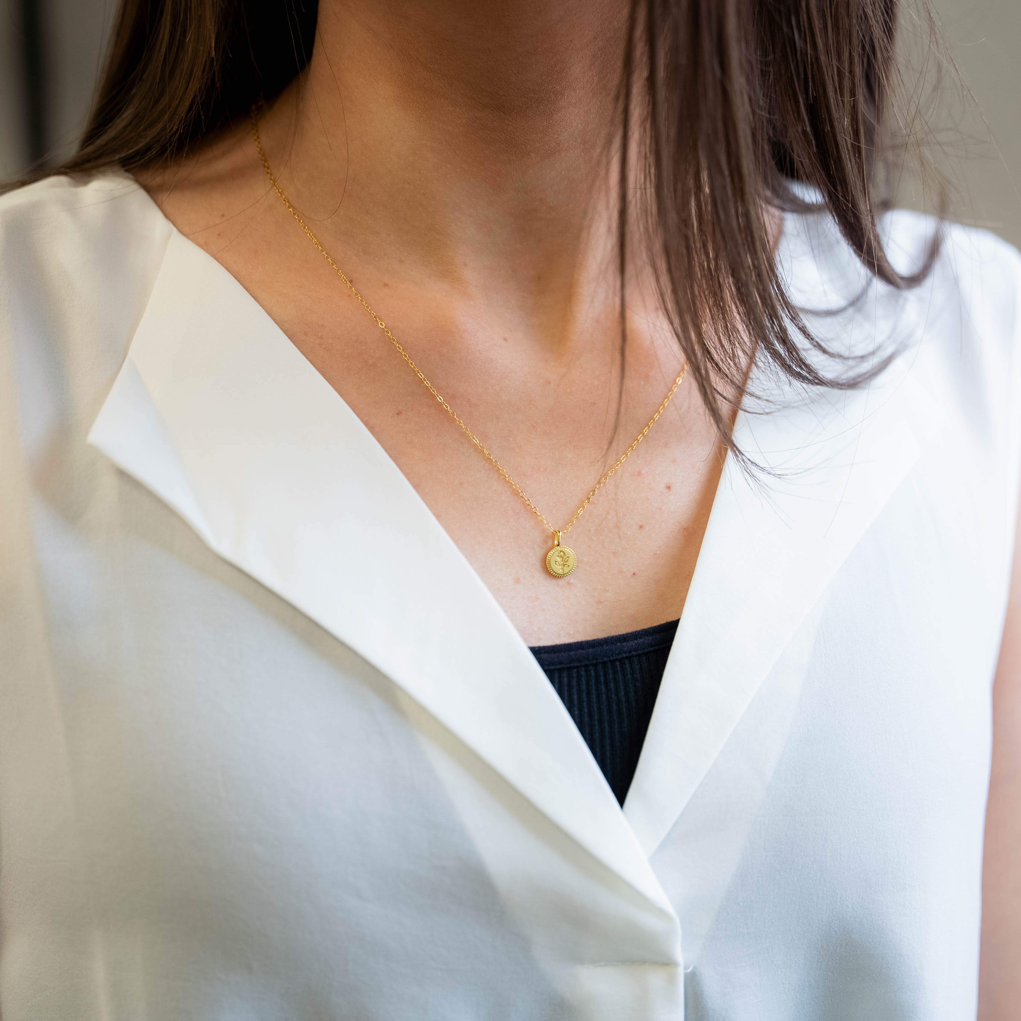 a woman wearing a white shirt and a gold necklace
