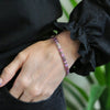a woman wearing a pink and purple bracelet