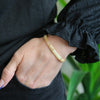 a woman wearing a black shirt and a gold bracelet