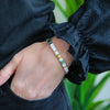a woman wearing a white bracelet with a green and yellow bead
