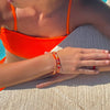 a woman wearing an orange bikini top and bracelet